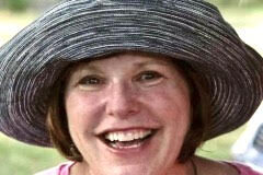 headshot of a smiling women wearing a sun hat