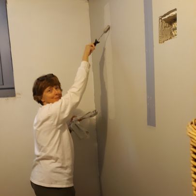 women in a white shirt painting a wall