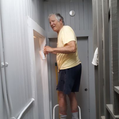 man standing on a stool painting a door frame