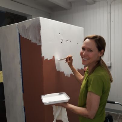 smiling women painting a piece of furniture