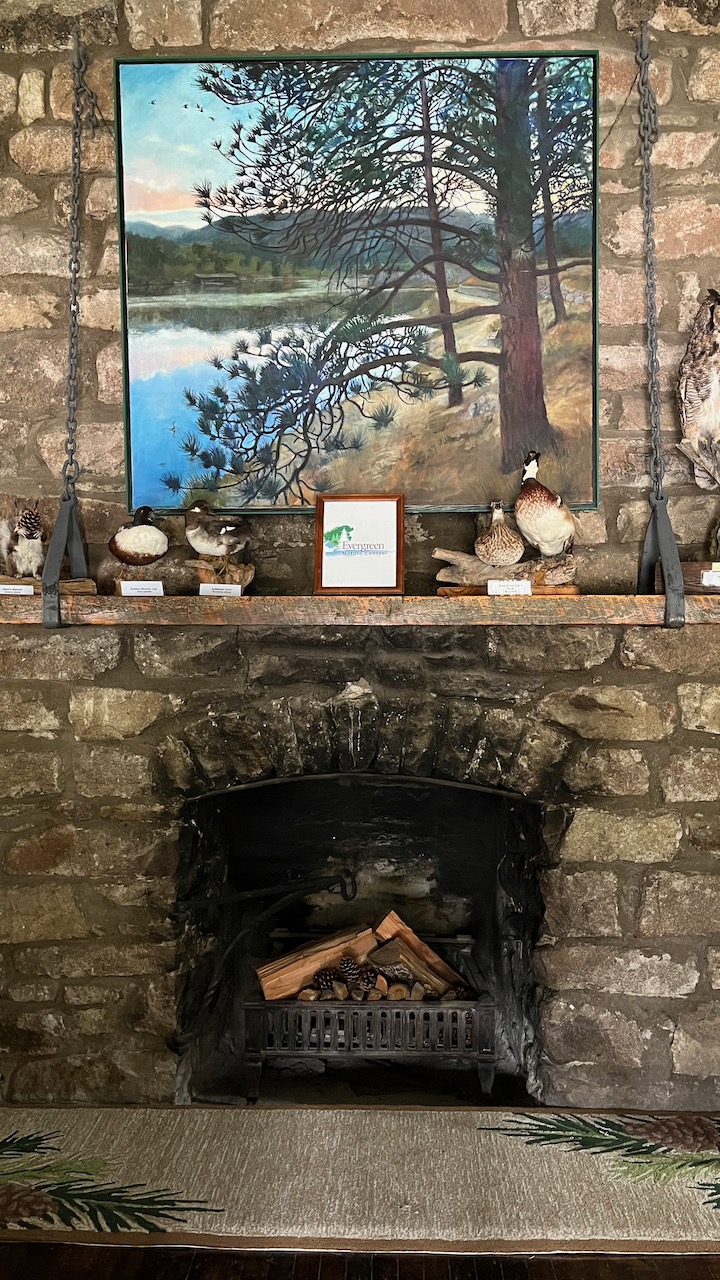 fireplace with painting and taxidermed animals on mantel