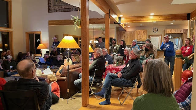 a bunch of people in chairs and on couches all facing toward something off the photo