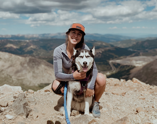 person sitting on top of a mountain holding a dog