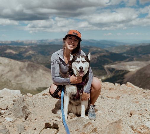 person sitting on top of a mountain holding a dog