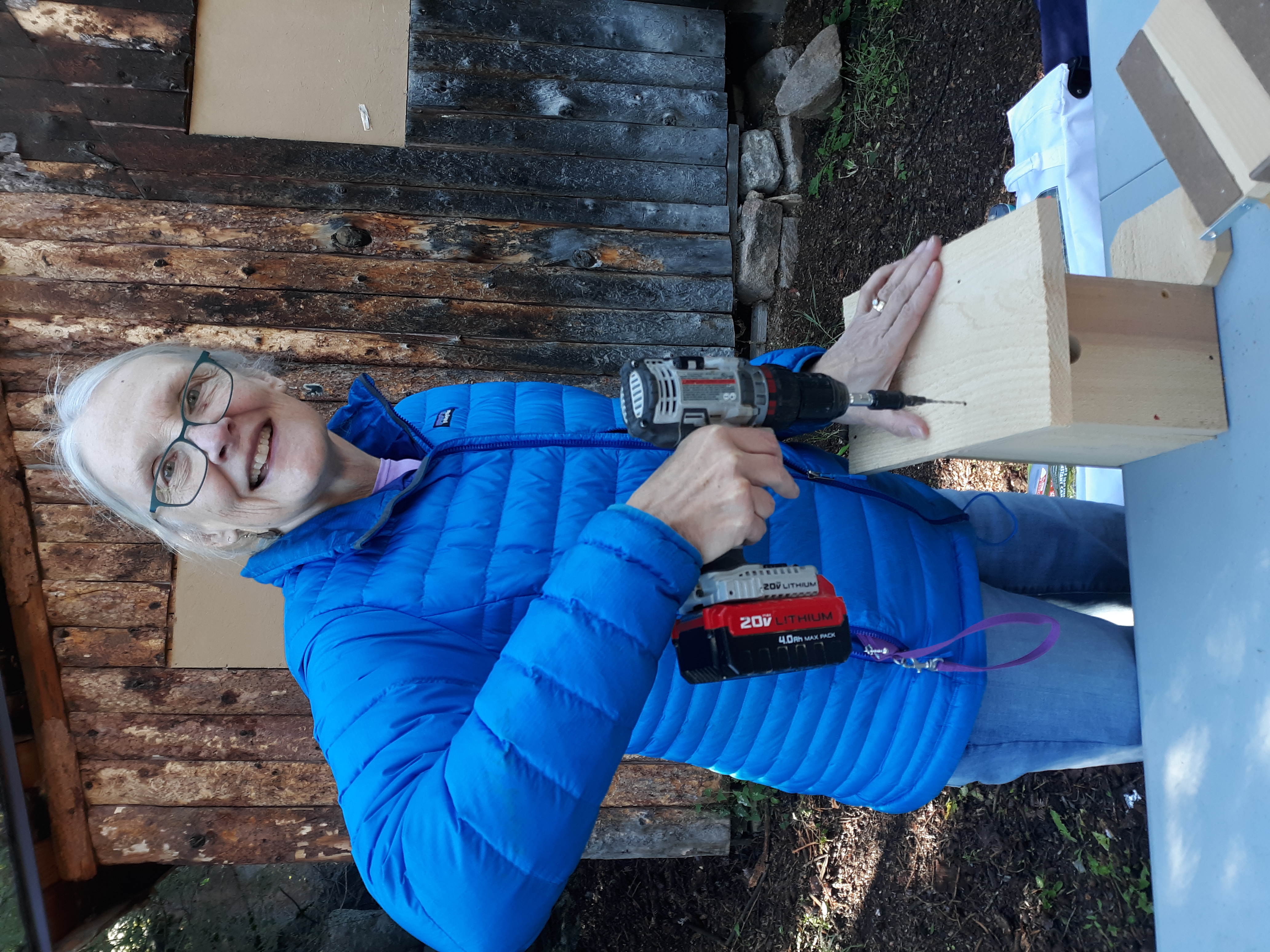 person holding drill over a birdbox