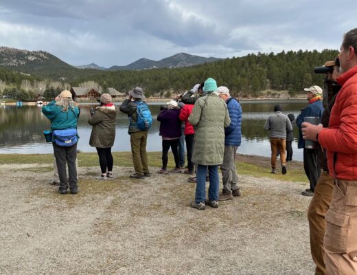about 20 people next to a lake holding binoculars