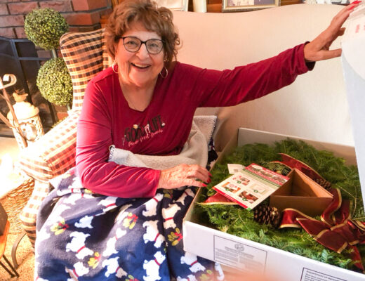 woman on couch opening a box with a wreath