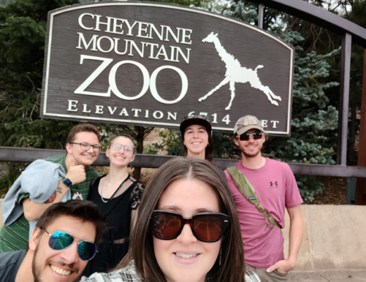 Six people in front of the Cheyenne Mountain Zoo sign