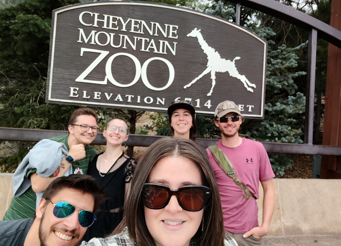 Six people in front of the Cheyenne Mountain Zoo sign
