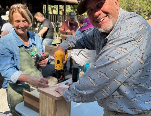 two people making a nestbox on a table outside