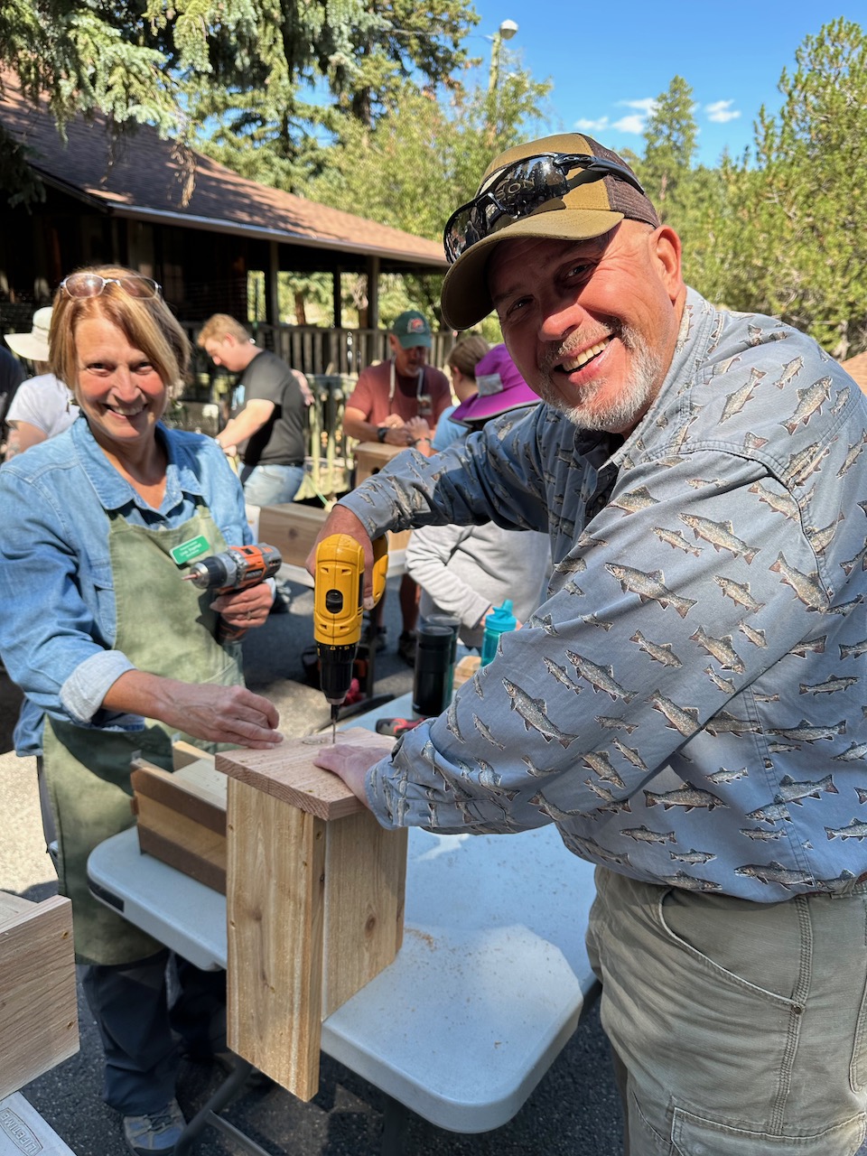 two people making a nestbox on a table outside