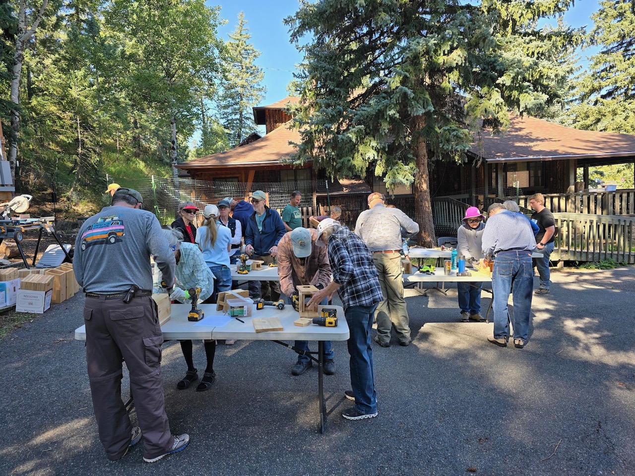 a bunch of people making nestboxes outside on tables