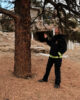 A woman in her black and yellow firewoman uniform gesturing to a ponderosa pine and talking about fire mitigation.
