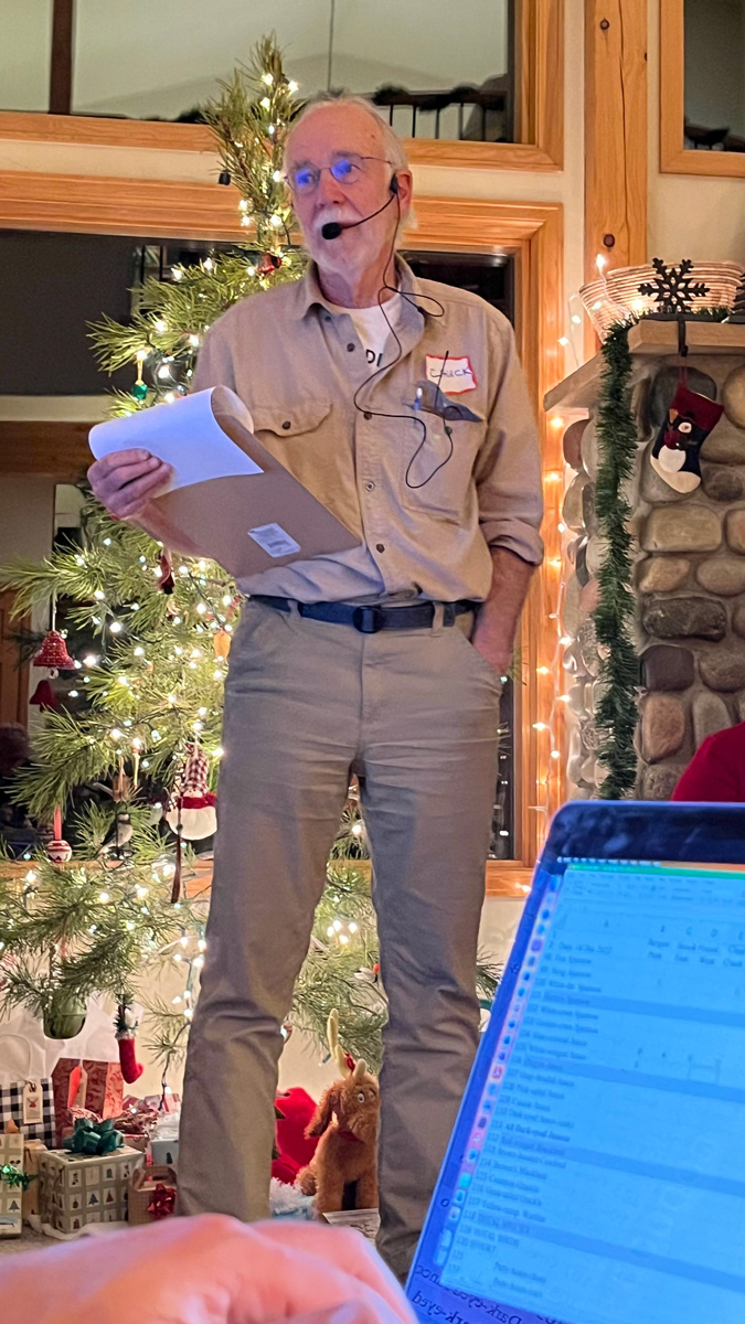 man with microphone standing in front of Christmas tree