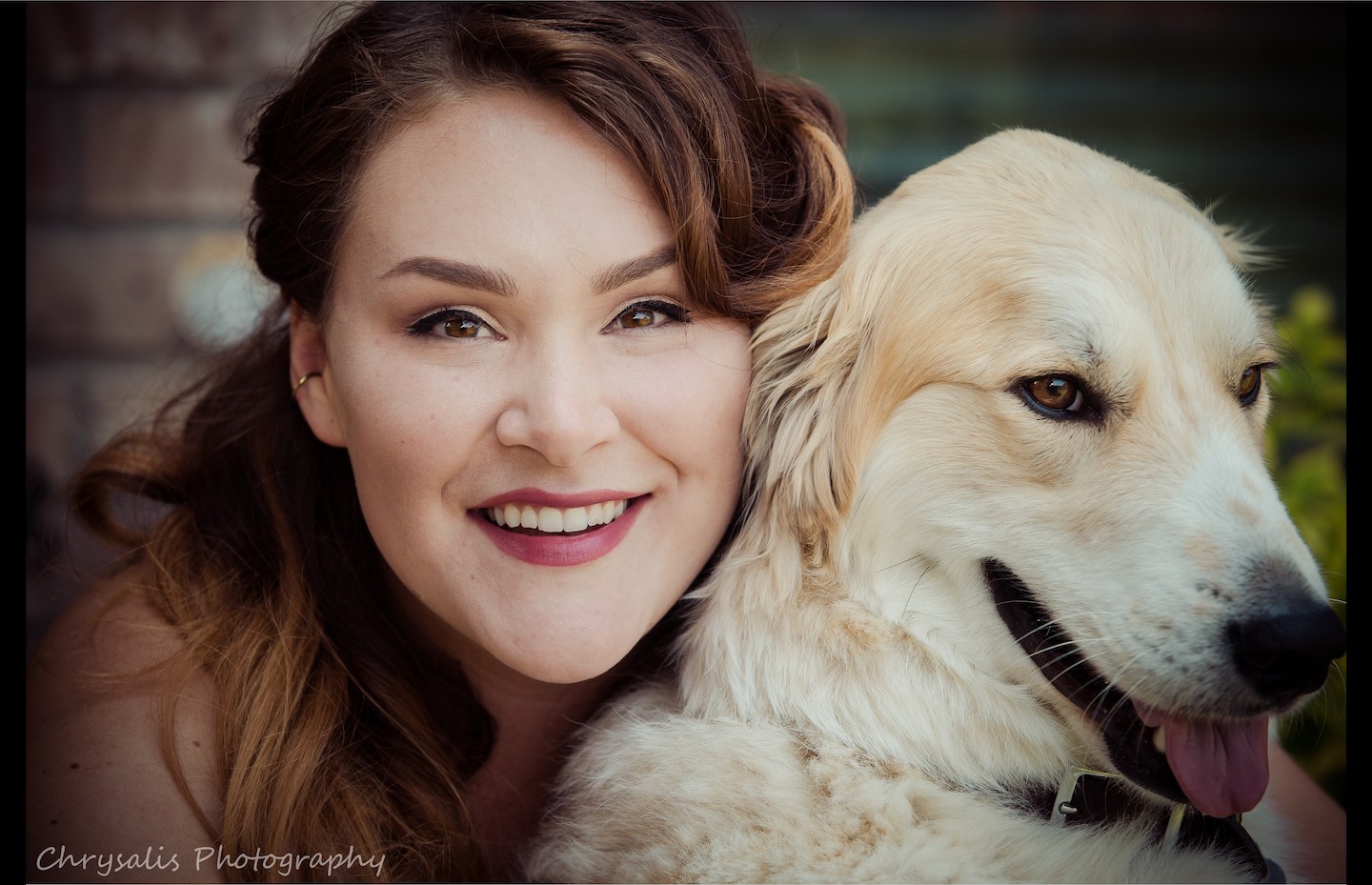 A curly red haired woman with her dog, a lighter golden retriever.