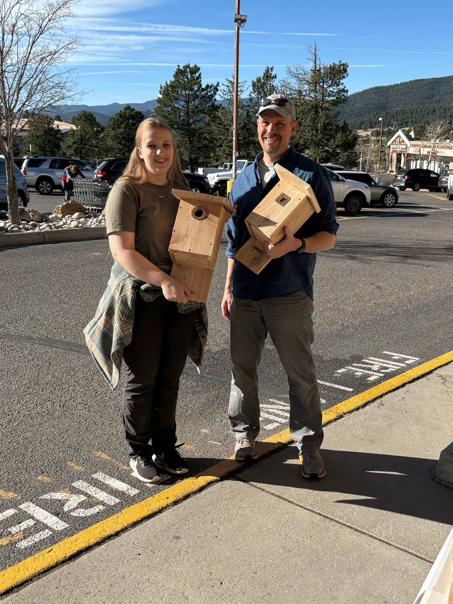 two people in a parking lot holding nestboxes